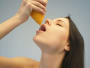 Naga nastolatka pije sok pomarańczowy